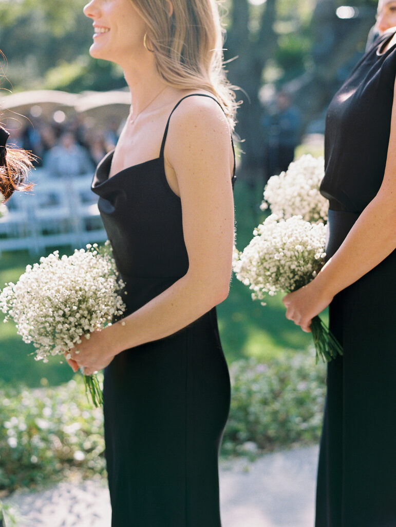 Bridesmaids in black silk dresses with babies breath bouquets