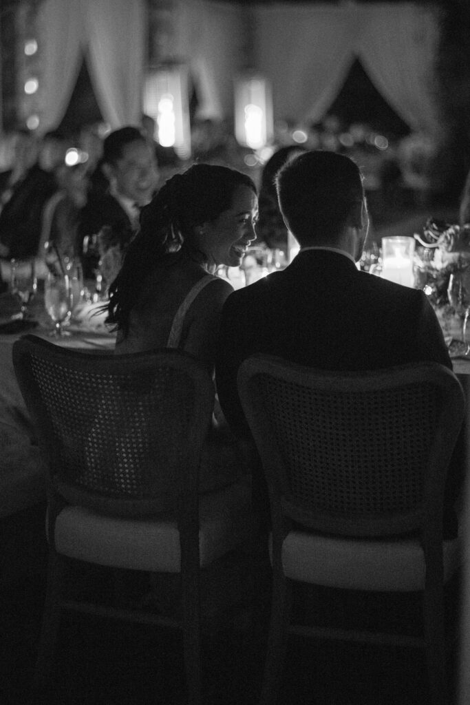 Black and white of bride and groom eating their outdoor candlelit dinner at their wedding reception