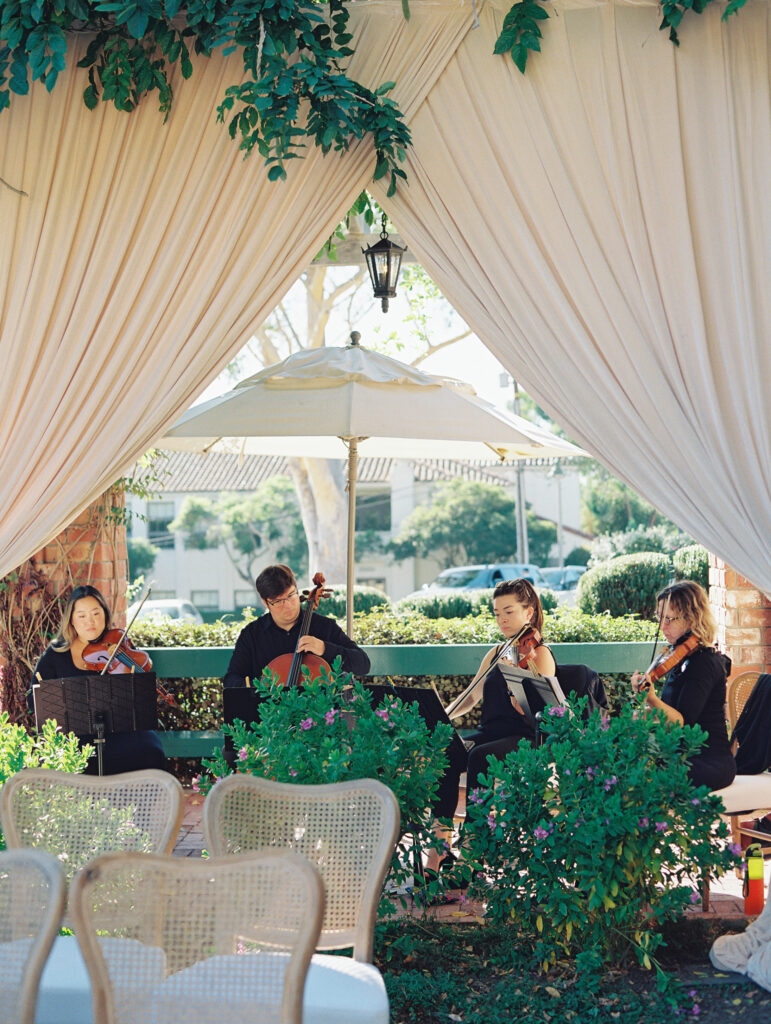 Wedding ceremony at the Belmond El Encanto hotel by the Lily Pond. Drapery hanging around the courtyard. String quartet playing.