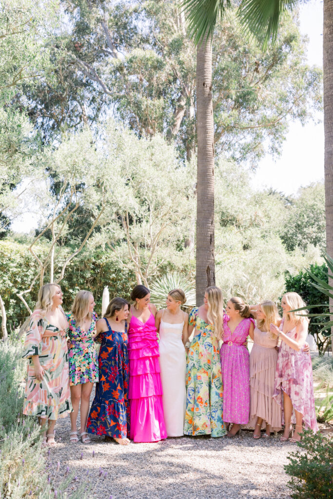 Montecito home backyard wedding cocktail hour in the garden. Bridal party all wearing colorful patterned dresses.