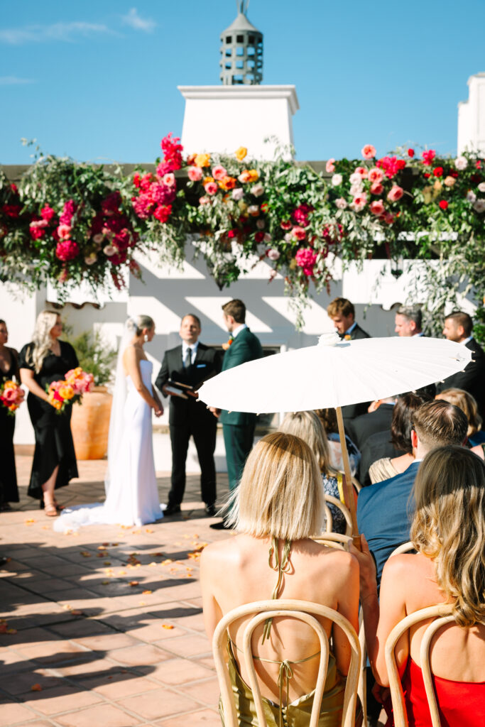 Wedding ceremony on Hotel Californian rooftop with large pink and orange floral arch