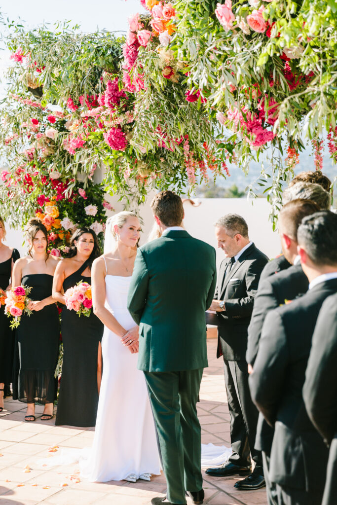 Wedding ceremony on Hotel Californian rooftop with large pink and orange floral arch. Image by Jodee Debes.