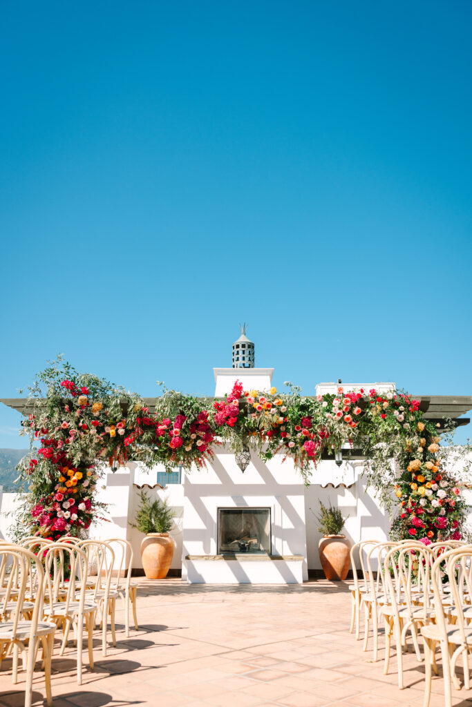 Pink and orange wedding ceremony arch at Hotel Californian Sirena Rooftop.