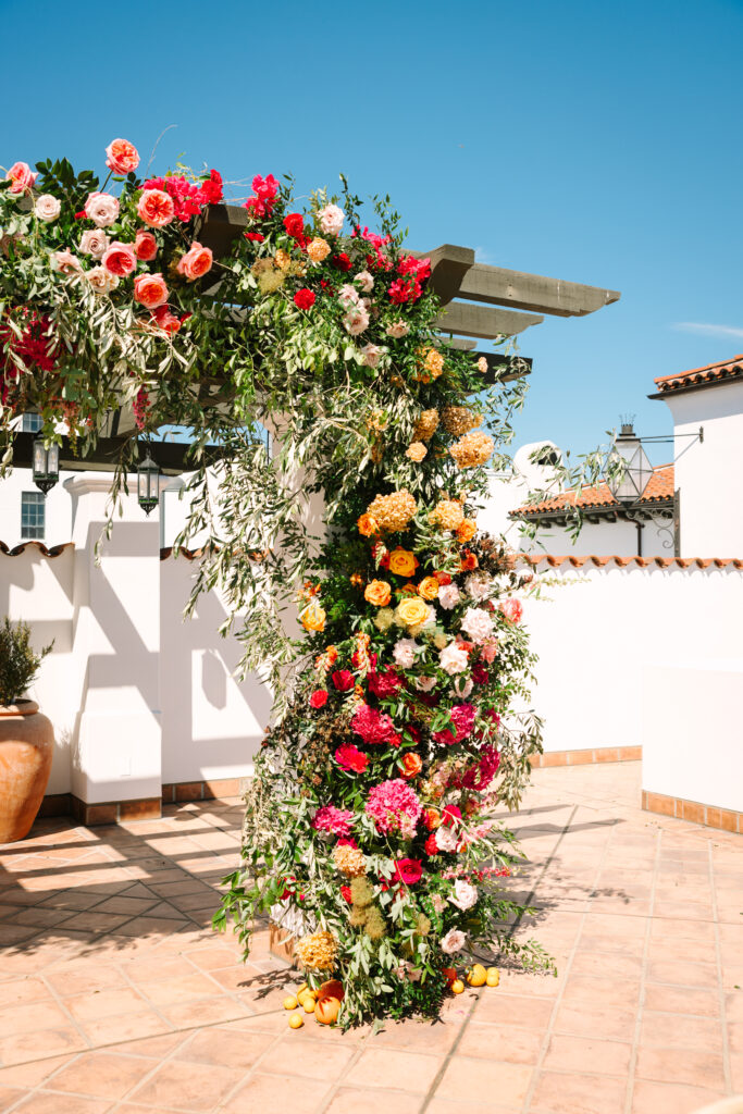 Wedding ceremony on Hotel Californian rooftop with large pink and orange floral arch