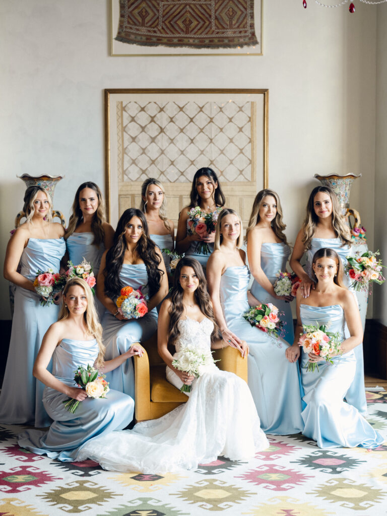 Indoor bridal party portrait with blue bridesmaid dresses and colorful bouquets. Samara Beauty