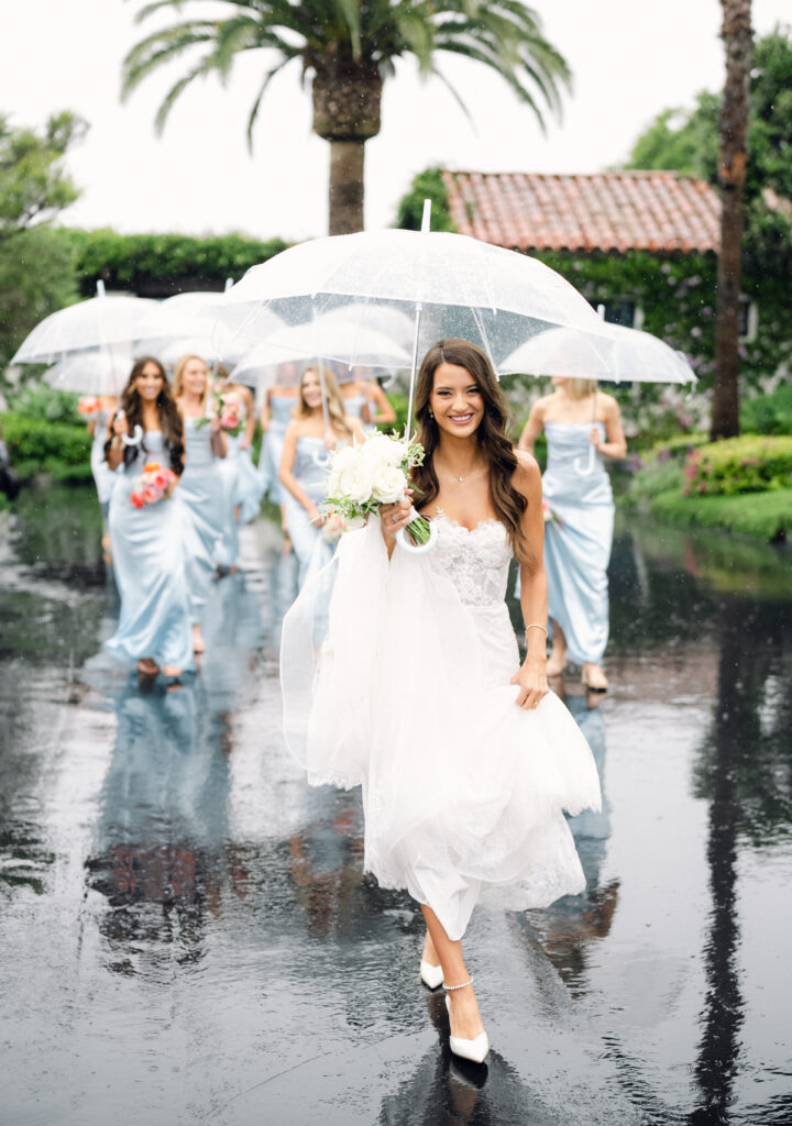 Bride and bridesmaids walking with clear umbrellas in the rain. Samara Beauty SB