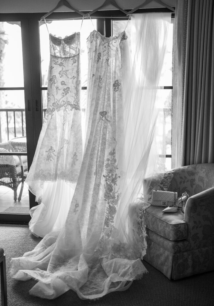 Bridal gowns and veil hanging on hangers with shoes and purse