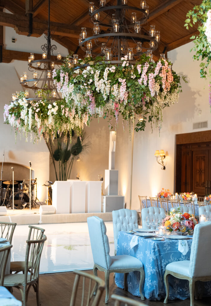 Colorful and Whimsical wedding reception inside the Montecito Country Club. Wisteria hanging down from chandeliers, custom dance floor 