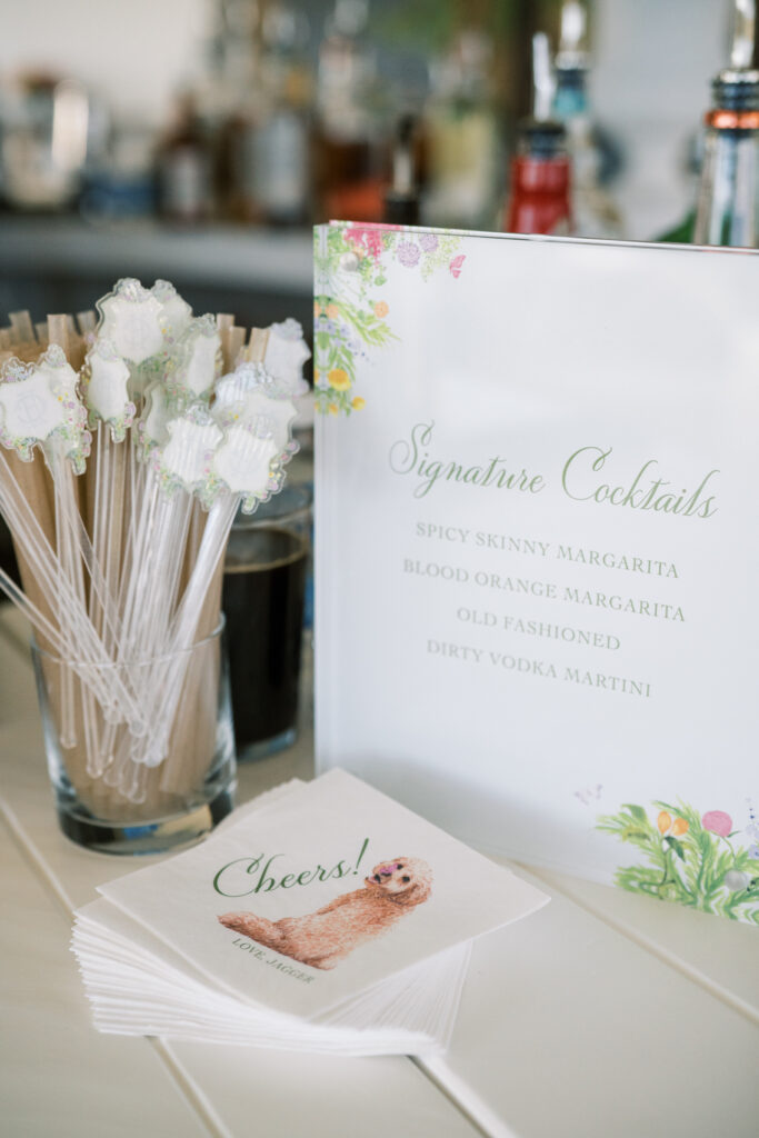 Wedding cocktail hour inside the Montecito Country Club with custom bar sign, stir sticks, and cocktail napkins