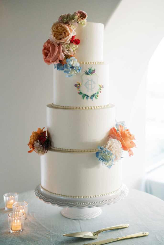 four-tiered wedding cake with couple's custom monogram and colorful flowers