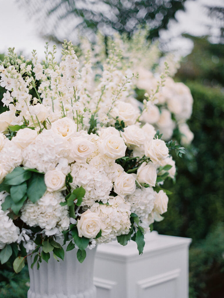 Wedding ceremony with white floral urn arrangements on top of white pillars at the Rosewood Miramar Beach resort