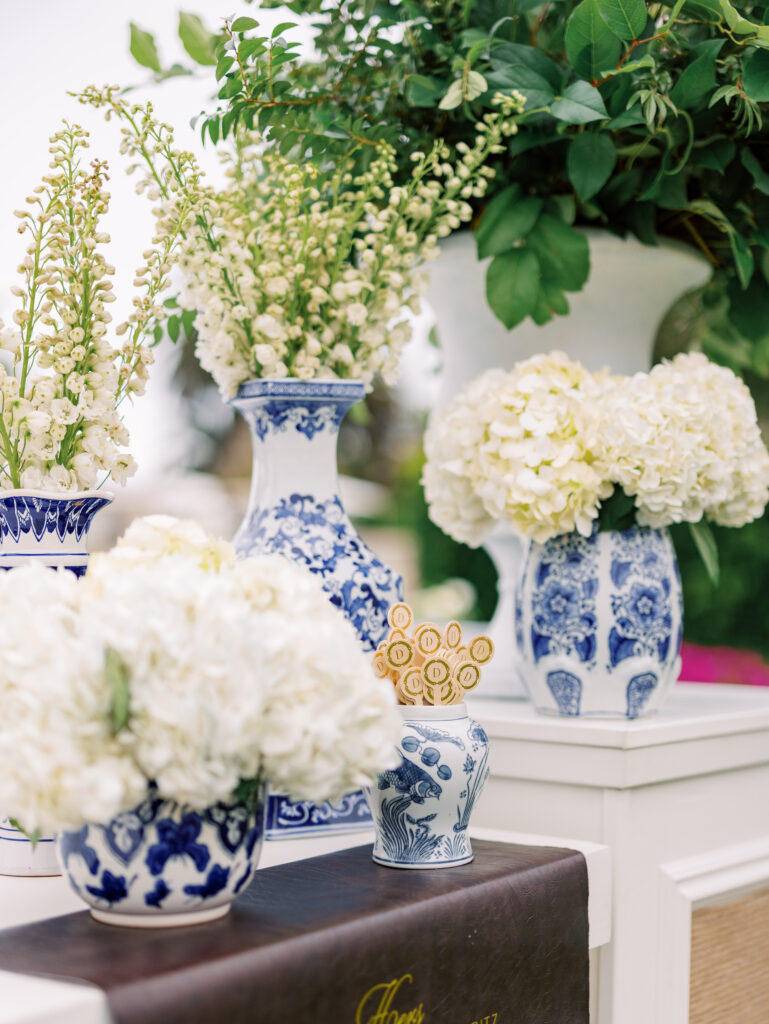 Large custom bar on the Rosewood Miramar Beach lawn at wedding cocktail hour with urns full of greenery and blue and white patterned vases