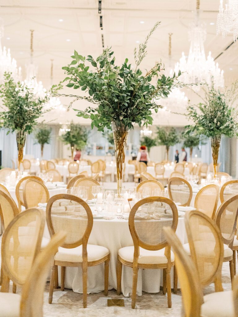 Neutral wedding reception in Rosewood Miramar Beach ballroom with tall olive tree table centerpieces