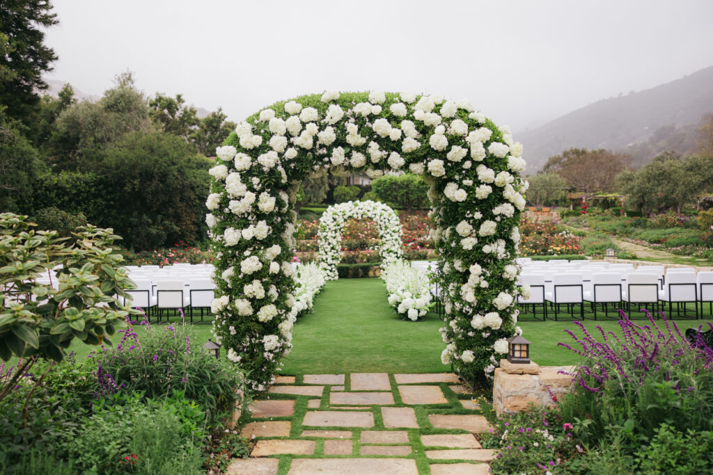 Wedding ceremony at San Ysidro Ranch with double rounded arches, floral aisle and white lush flowers.