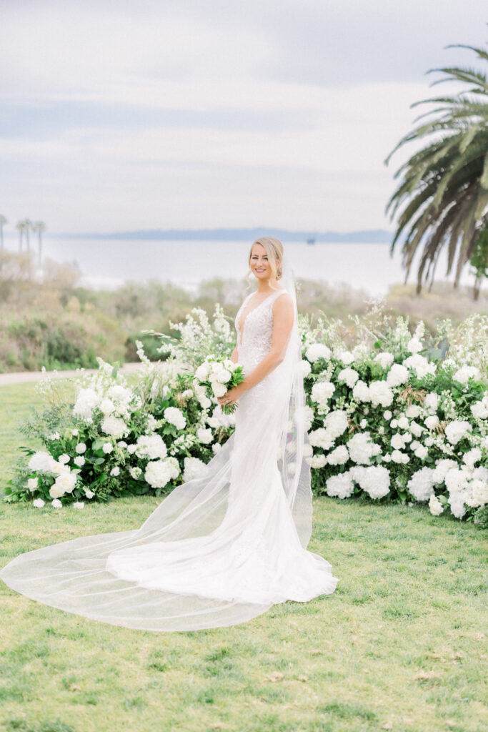 Wedding ceremony with ocean view at The Ritz Carlton Bacara with grounded half-circle arch with white flowers