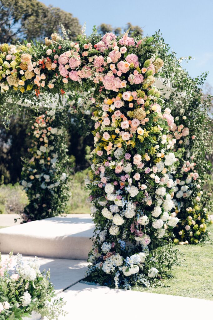 Sikh Indian Wedding at the Ritz Carlton Bacara with ocean view in background. Very large mandap and floral aisle covered in colorful rainbow flowers and carpeted ground and aisle with pillows.