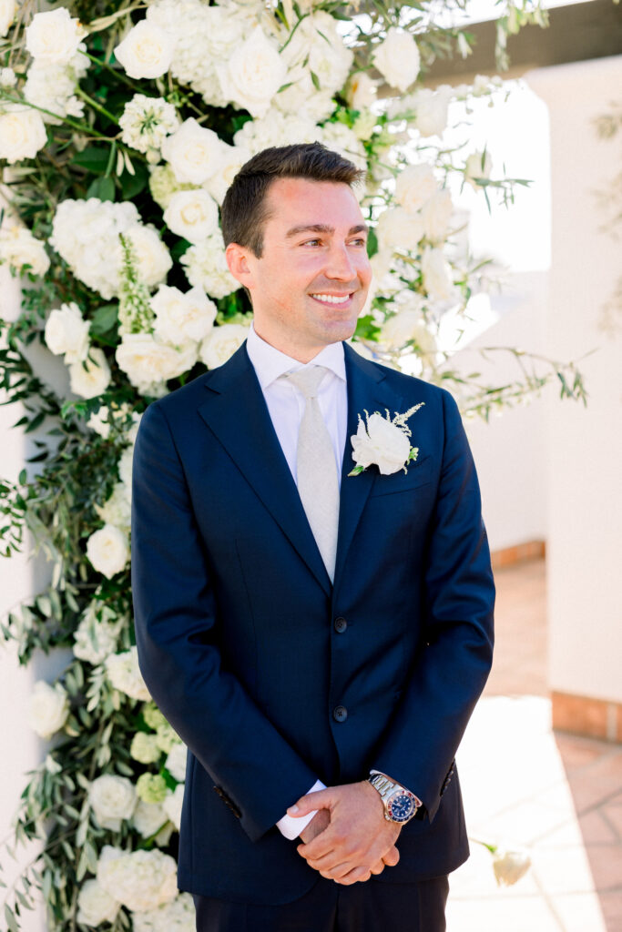 Two grooms getting married in front of triple wedding arch at Hotel Californian Sirena Rooftop with white flowers. Gay wedding in Santa Barbara.