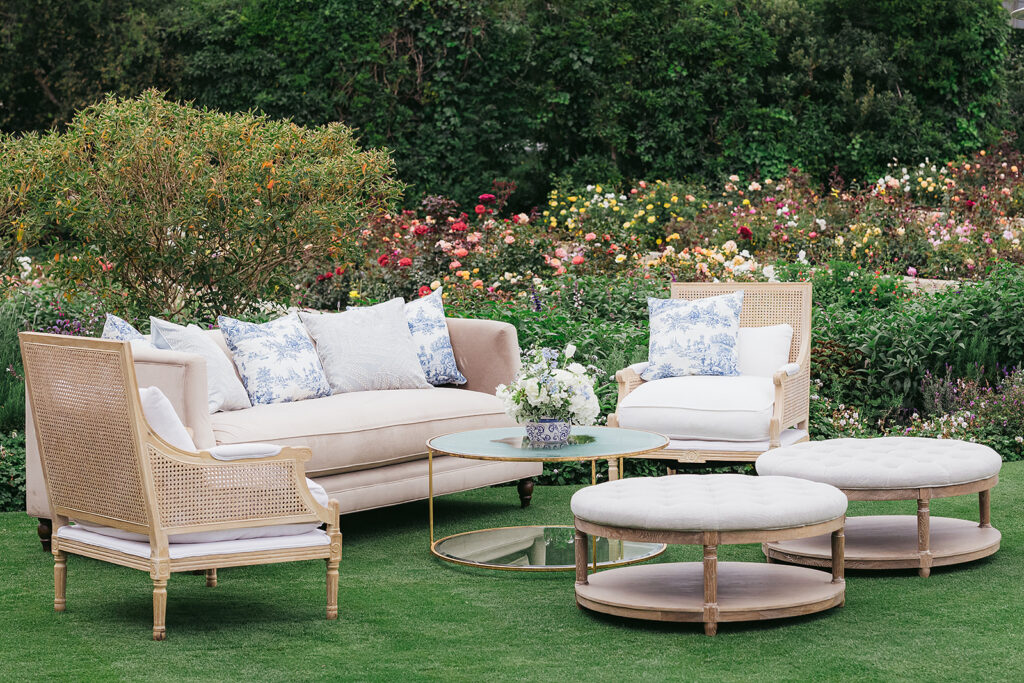 Neutral and elegant upholstered lounge with blue and white throw pillows in garden at wedding