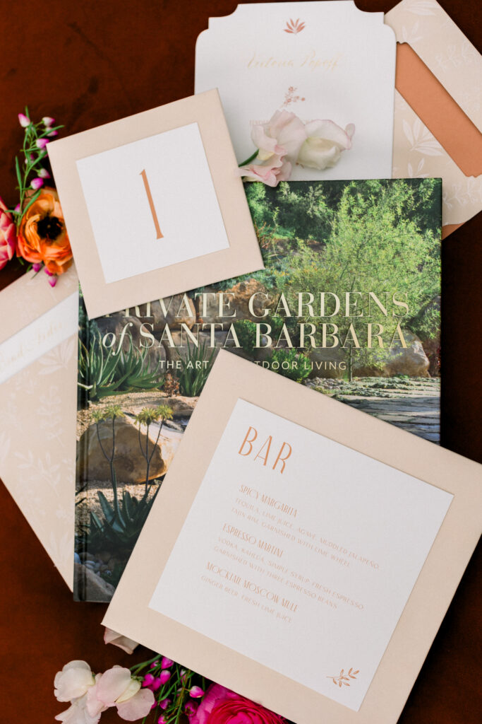 Wedding flatlay of Coffee table book, table number, menu, and bar sign.