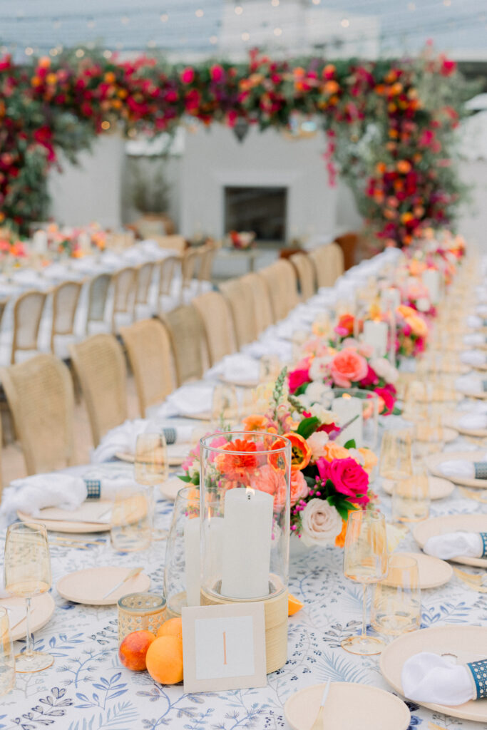 Tablescape for Wedding Welcome Party at Hotel Californian in Santa Barbara, Ca. With colorful flowers, patterned linens, and citrus details. Pillar candles with table number.