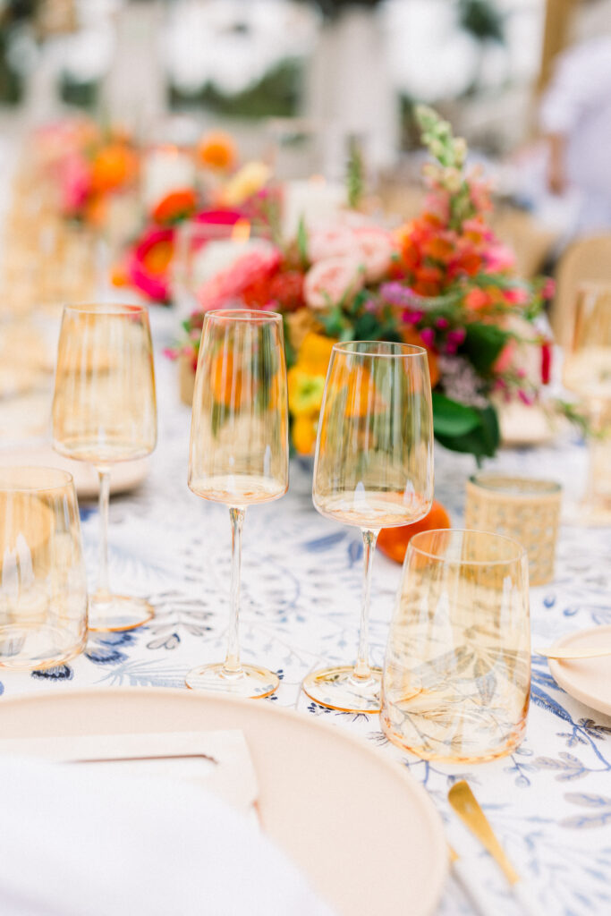 Destination Wedding Welcome Party at Hotel Californian in Santa Barbara, Ca. With colorful flowers, patterned linens, and citrus details. Yellow glassware set at dinner table.