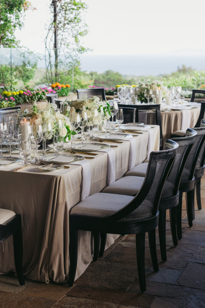 Wedding reception dinner with ocean view at San Ysidro Ranch's award-winning restaurant, Stonehouse. Neutral velvet table linens, black and white upholstered dining chairs, white and green floral centerpieces.