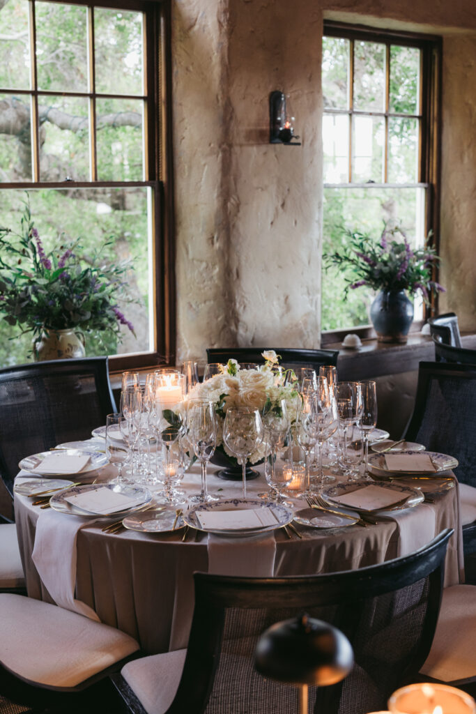 Wedding reception dinner at San Ysidro Ranch's award-winning restaurant, Stonehouse. Neutral velvet table linens, black and white upholstered dining chairs, white and green floral centerpieces.