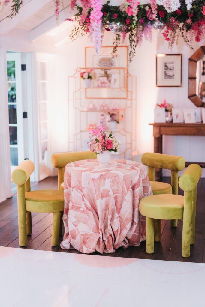 Wedding dance floor with pink florals hanging down from chandelier, pink linens and green upholstered chairs. Custom white dance floor with pink floral pattern.