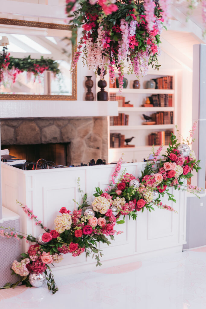 Wedding dance floor with pink floral installations on DJ booth and hanging down from chandelier. Custom white dance floor with pink floral pattern and couple's monogram