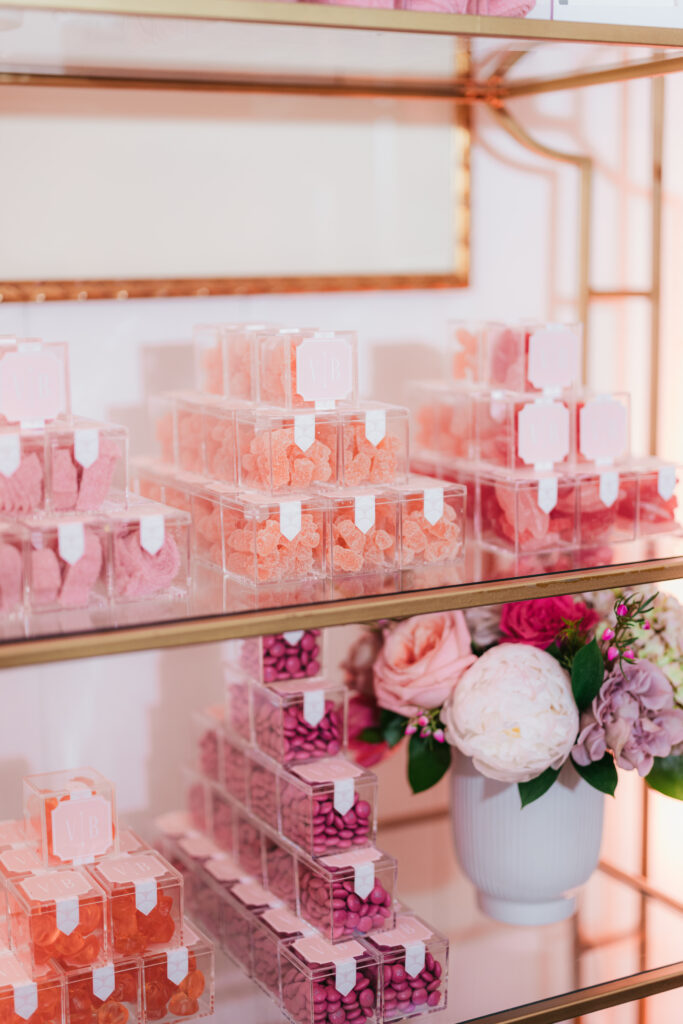 Gold shelf wit custom candy boxes as wedding favors with couple's monogram on sticker and lots of pink candy