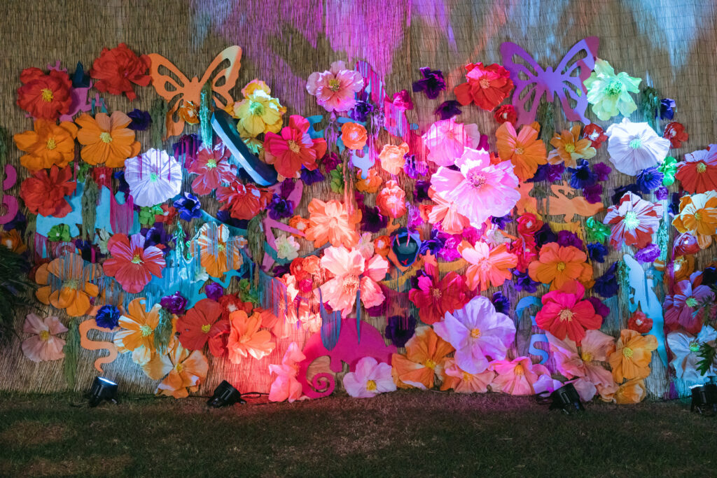 Photo backdrop with paper flowers and large snake prop and butterflies