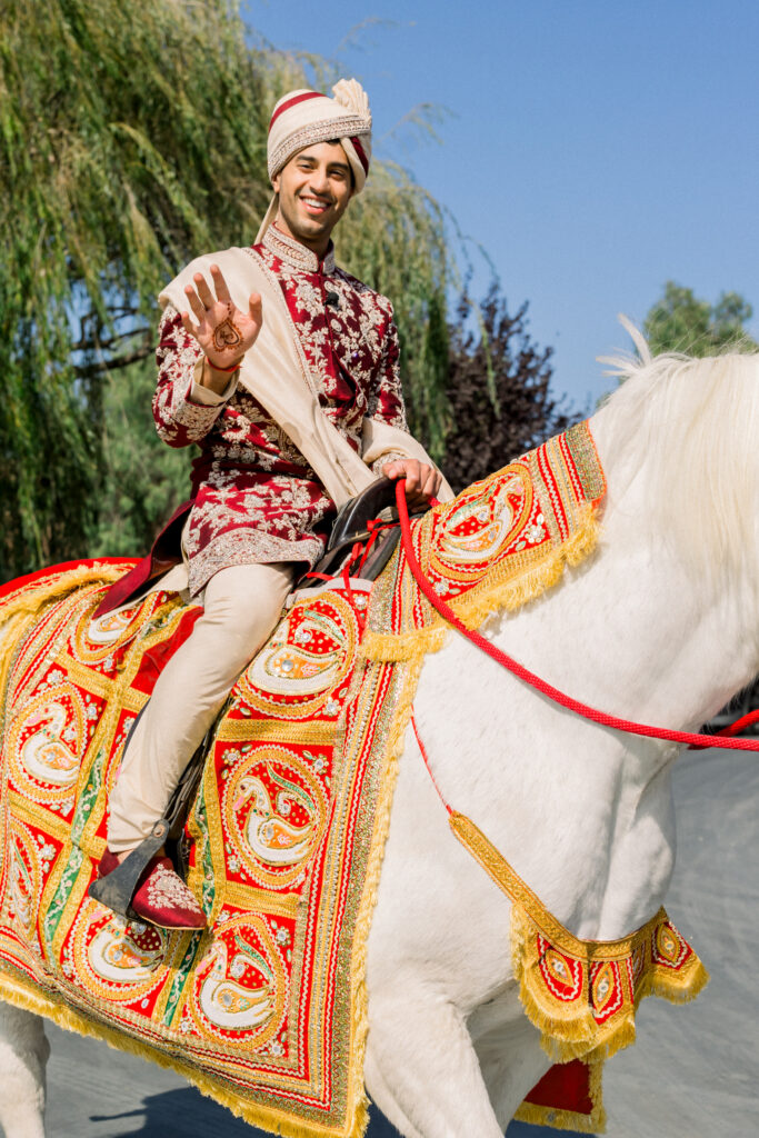 Groom on white horse at Baraat at Multicultural wedding